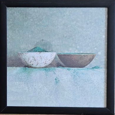 Two ceramic bowls on a textured surface with a black frame.