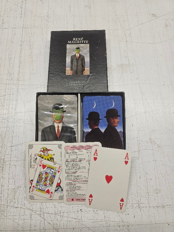 Playing cards with Magritte artwork on a textured surface