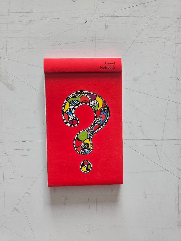 Red notebook with a colorful question mark design on a gray surface