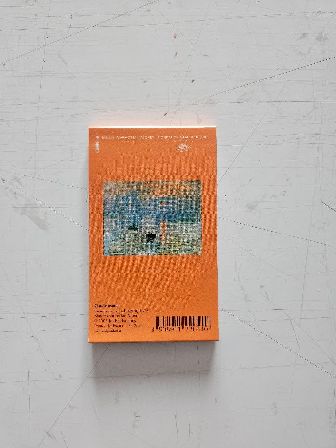 Book cover with a painting of a landscape on an orange background, placed on a textured white surface.