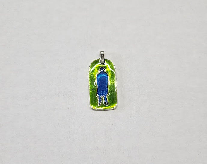 Pendant with blue figure on a green background on a gray surface