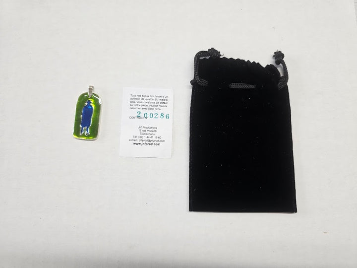 Green pendant with blue heart on a white card, next to a black drawstring bag on a light gray background